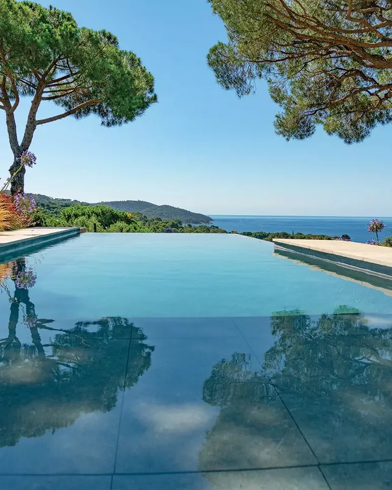 Piscine à débordement construite par Diffazur, face à la mer, entre deux pins parasols